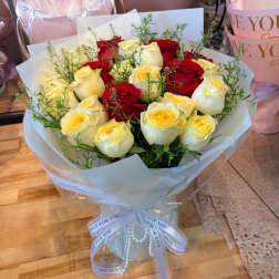 Bouquet of red and cream roses wrapped in white paper
