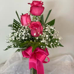 Pink roses in a clear glass vase with a bright ribbon