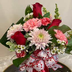 Bouquet of red roses, pink carnations, and pale chrysanthemums with a heart-patterned ribbon
