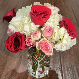 Bouquet of red, pink, and white roses in a clear glass vase