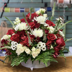 Red and white mixed flower arrangement in a round box