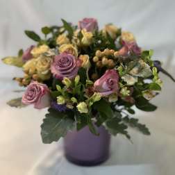 Lavender and cream rose bouquet in a purple vase
