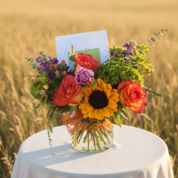 Bouquet of roses and a sunflower in a glass vase with a card