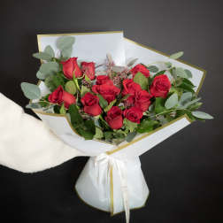 Bouquet of red roses wrapped in white paper with gold trim