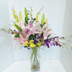 Pink lilies and purple orchids in a tall glass vase