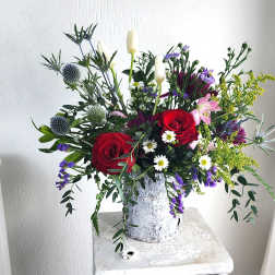Mixed bouquet with red roses, white lilies, and purple flowers in a white vase