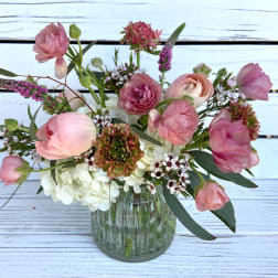 Small glass vase with pink ranunculus and mixed flowers in a loose, airy arrangement