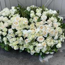 Large white rose arrangement with greenery on the ground