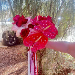 Handheld bouquet of red and pink roses with bright pink anthuriums
