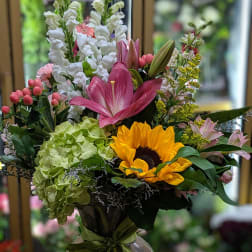 Mixed bouquet in a glass vase with sunflowers, lilies, and hydrangeas