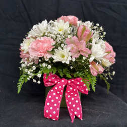 Pink and white flowers in a green vase with a polka-dot ribbon