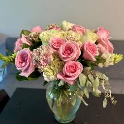 Pink roses and pale flowers arranged in a glass vase