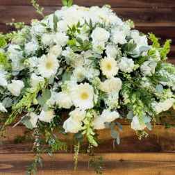 White floral casket spray with roses and daisies
