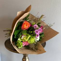 Wrapped bouquet of mixed flowers with an orange rose and pink blooms