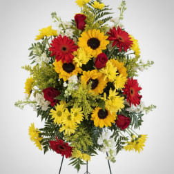 Standing floral spray with red roses, yellow daisies, and white accents