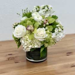 White roses and green hydrangeas arranged in a dark glass vase