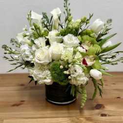 White and green floral arrangement in a black vase