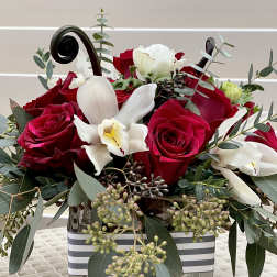 Red roses and white orchids in a glass vase with eucalyptus
