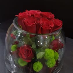 Red roses and green pom-pom flowers in a clear glass bowl