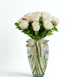 White roses in a clear glass vase with a ribbon bow