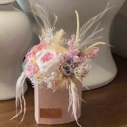 Pink and white rose arrangement in a blush box with dried feathers