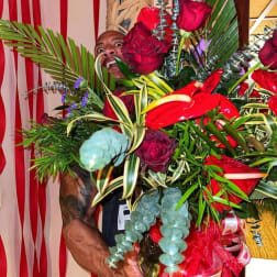 Large bouquet of red roses and tropical foliage held by a man