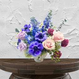 Bouquet of purple, pink, and blue flowers in a white vase