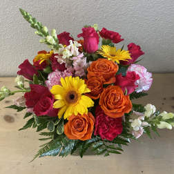 Mixed bouquet of orange and pink roses with yellow daisies in a vase