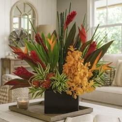 Tropical flower arrangement in a black square vase with red, orange, and green blooms