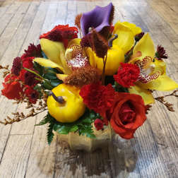 Colorful floral arrangement with roses, calla lilies, and orchids in a gold vase