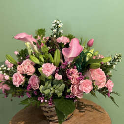 Pink roses and calla lilies arranged in a wicker basket