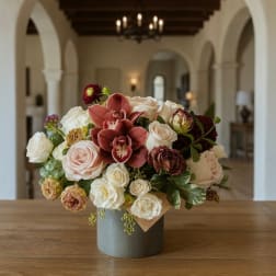Bouquet of roses and orchids in a gray hatbox