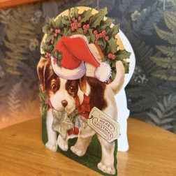 Christmas card with a puppy wearing a Santa hat and holly wreath