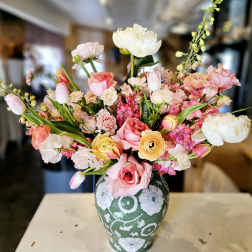 Mixed pink, white, and yellow flowers arranged in a patterned vase