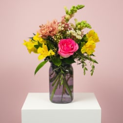 Pink rose and yellow mixed flowers in a glass vase