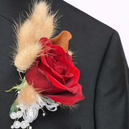 Red rose boutonniere with beige dried accents on a black suit lapel