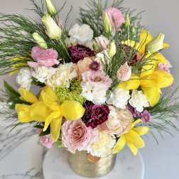 Arrangement of yellow tulips, pink roses, carnations, and white blooms in a gold vase