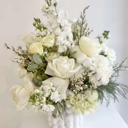 White floral arrangement in a white vase with roses and tall blooms