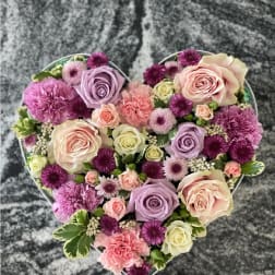 Heart-shaped floral arrangement with pink, lavender, and cream blooms