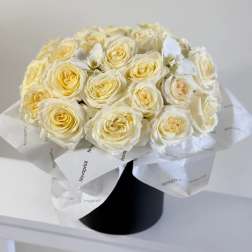 Bouquet of cream roses wrapped in white paper in a black box