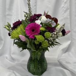Mixed bouquet in a green glass vase with pink, white, and green blooms