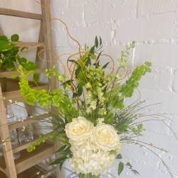 White roses and hydrangeas in a clear vase with green accents