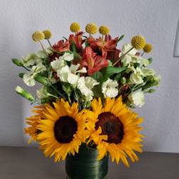 Sunflowers, alstroemeria, and white carnations in a glass vase