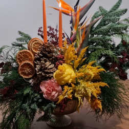 Tropical floral arrangement with orange candles in a pedestal vase