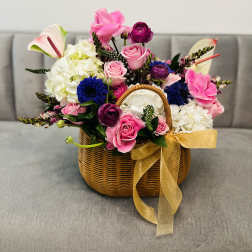 Basket arrangement of pink and white flowers with a gold ribbon