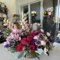 Mixed pink and purple flower arrangement in a woven basket