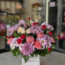 Pink and red mixed bouquet in a white gift bag