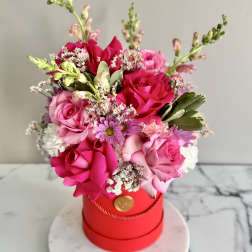 Pink and red rose bouquet in a red hat box on a round base