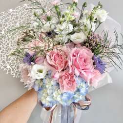 Handheld bouquet of pink and white roses with blue hydrangeas