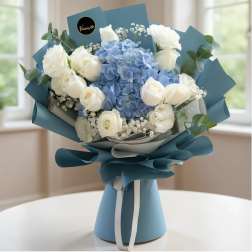 Bouquet of white roses and blue hydrangeas wrapped in blue paper
